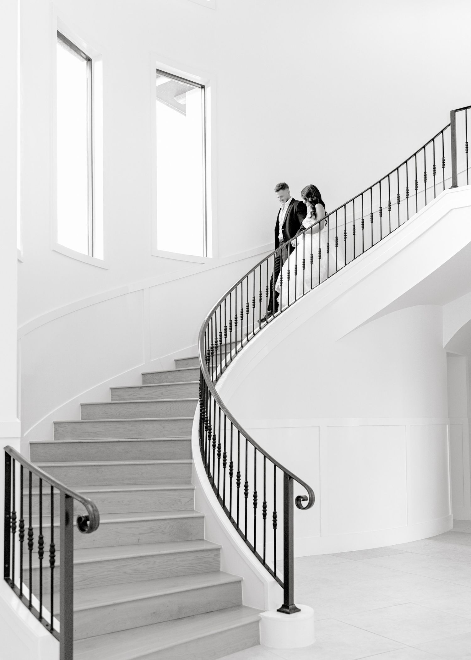 A minimalist white staircase with black metal railings shown from four different angles in a modern interior space.