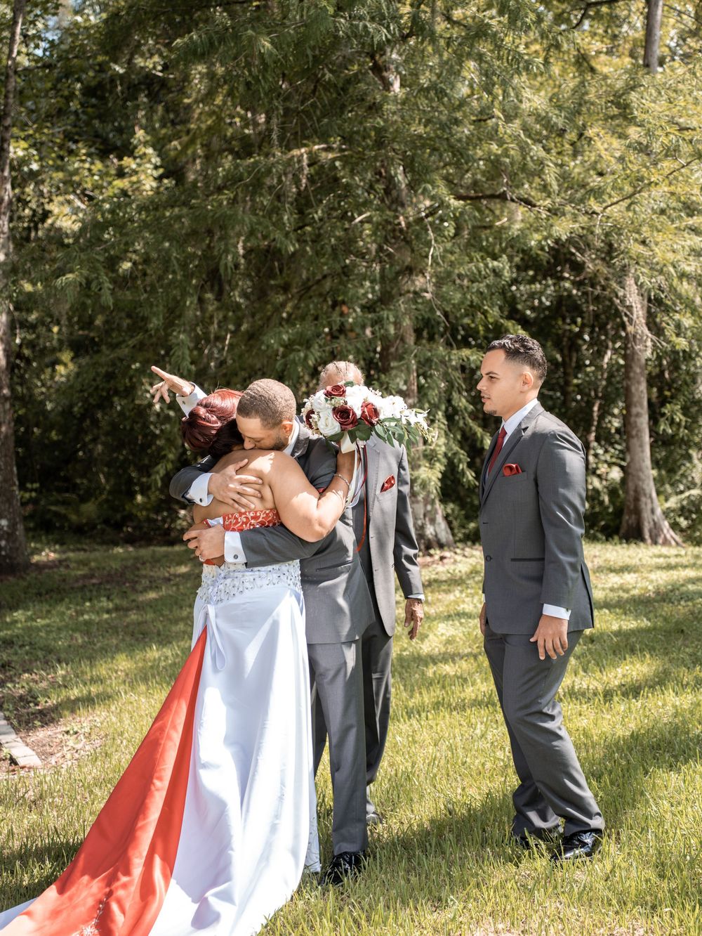 A wedding ceremony takes place outdoors under tall trees with coral and grey color accents in Tampa Florida