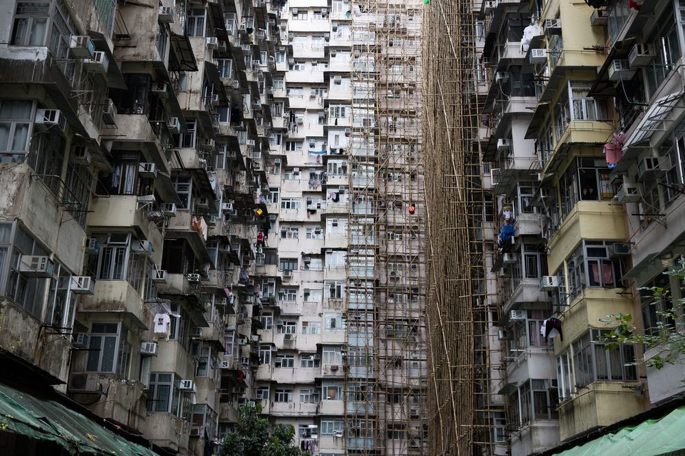 Dense Hong Kong residential apartment building facade with bamboo scaffolding extending between buildings.