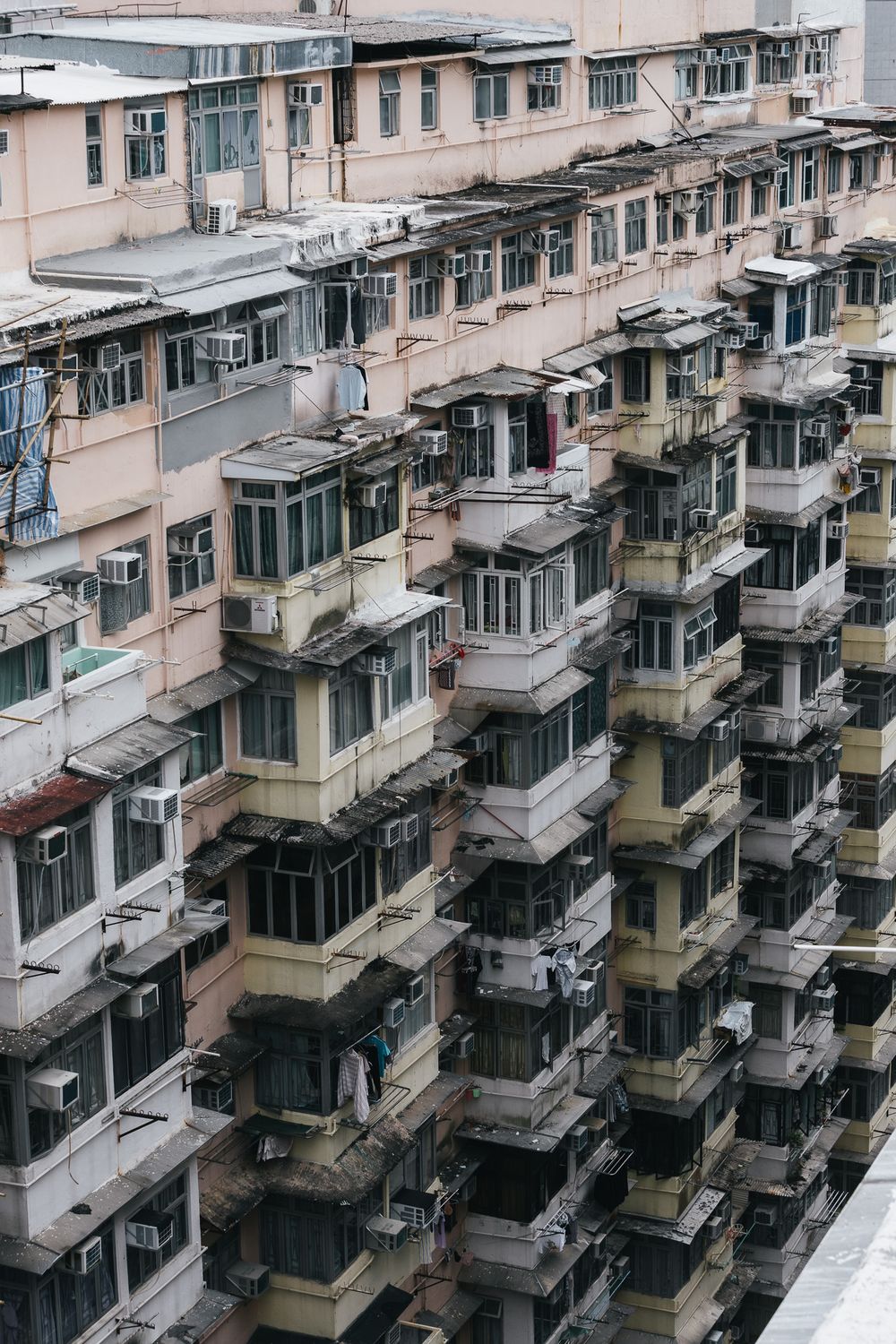 Dense Hong Kong residential apartment building facade with air conditioners and enclosed balconies.