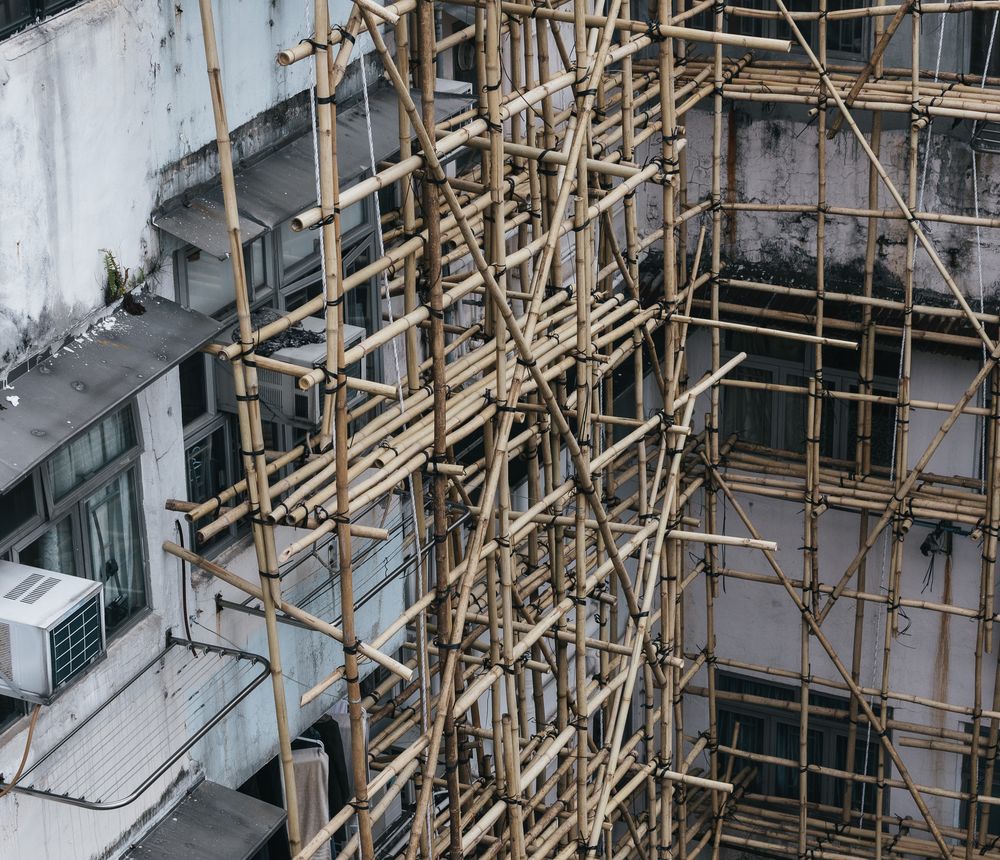 Bamboo scaffolding covering the exterior of an old urban residential building under renovation.
