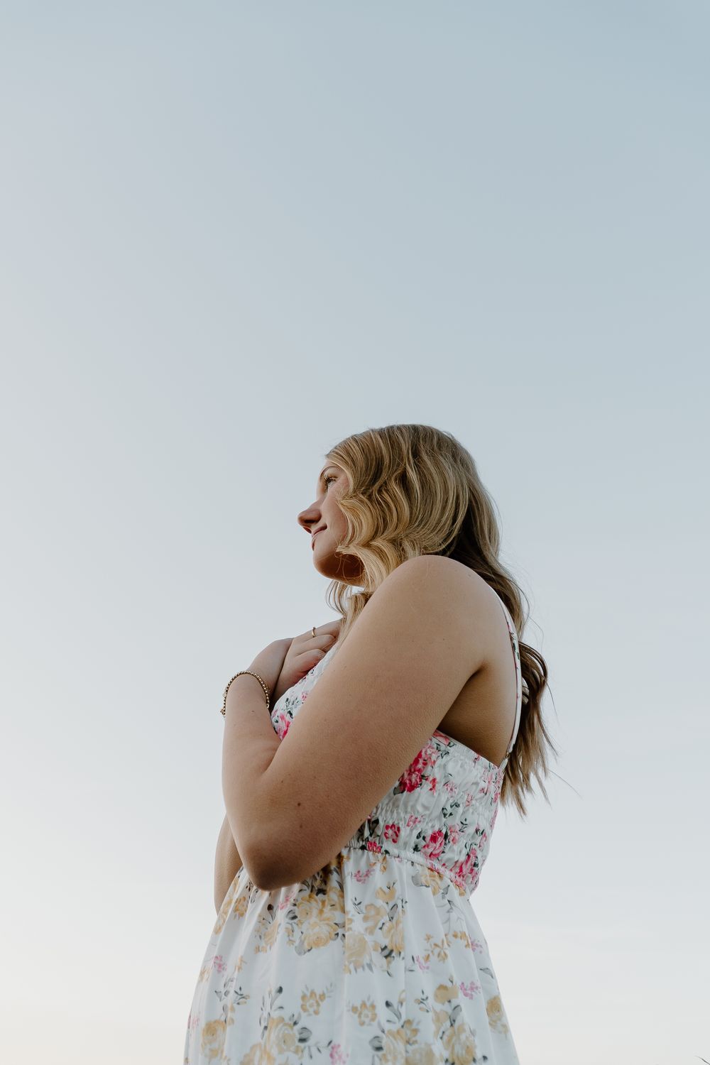 A person in a floral dress laughs joyfully while looking upward against a light background.