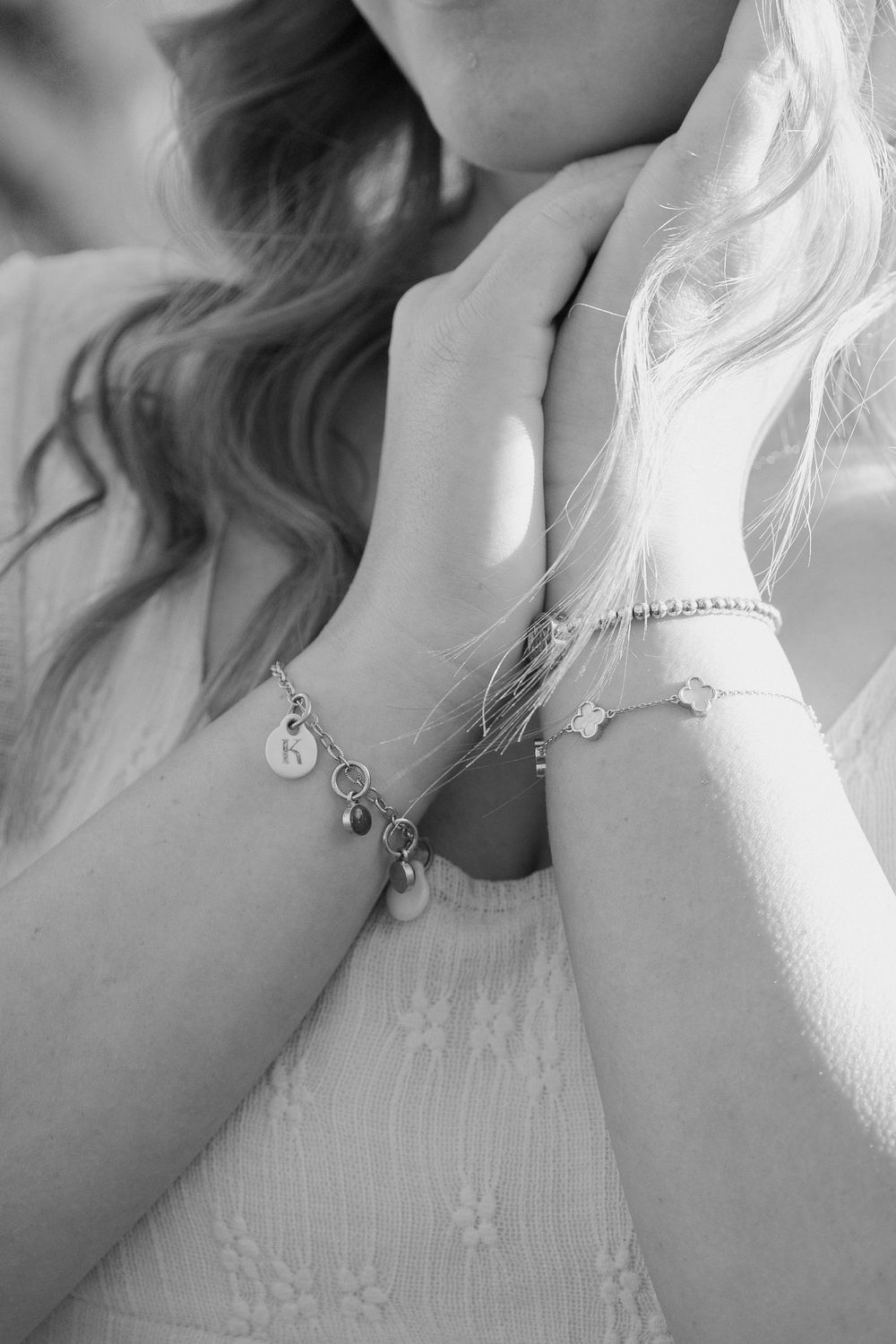 A series of black and white close-up photos showing a person wearing delicate jewelry and a light-colored top.