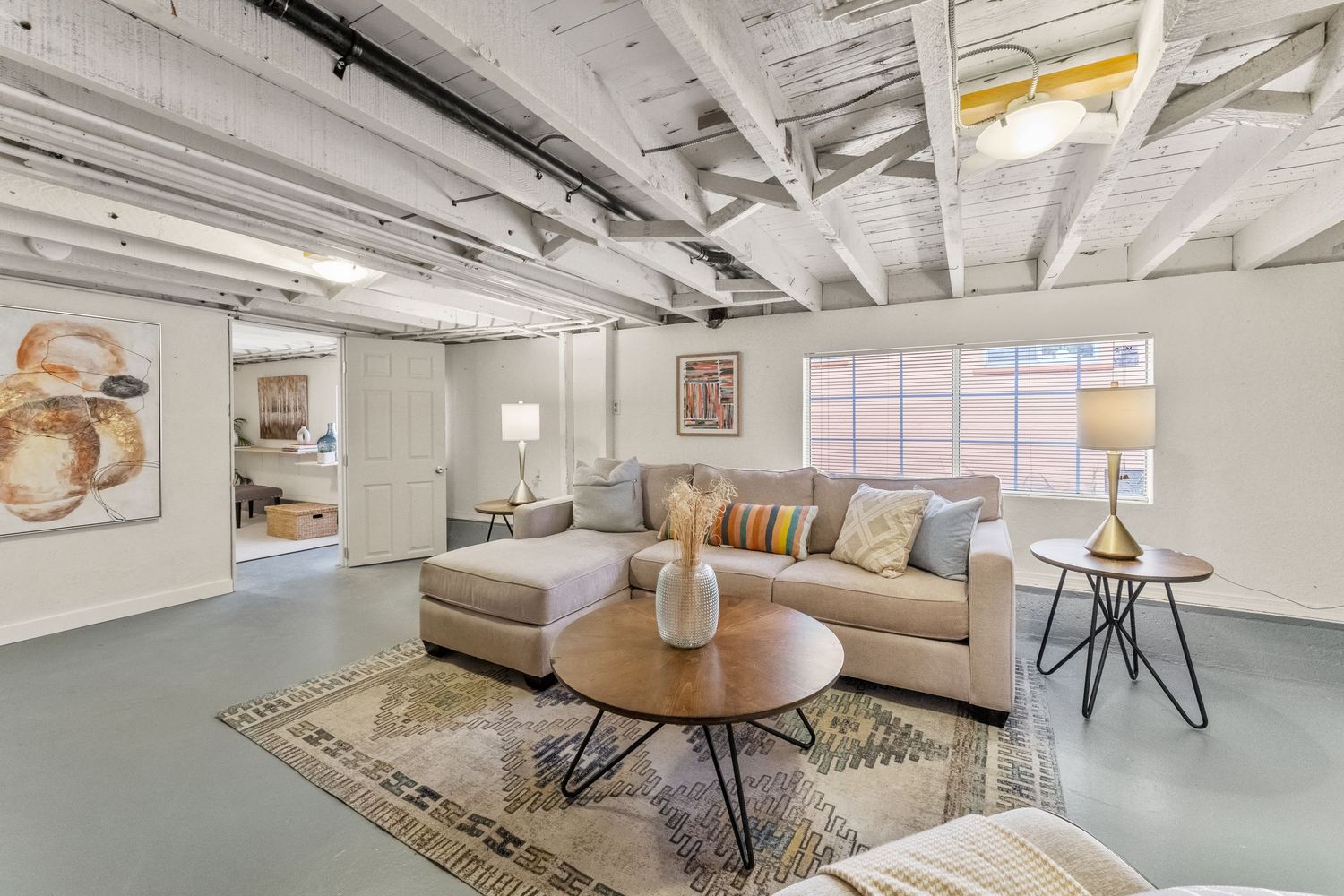 Industrial chic workspace with exposed beams and pipes features modern furniture and white walls for a minimalist studio look.