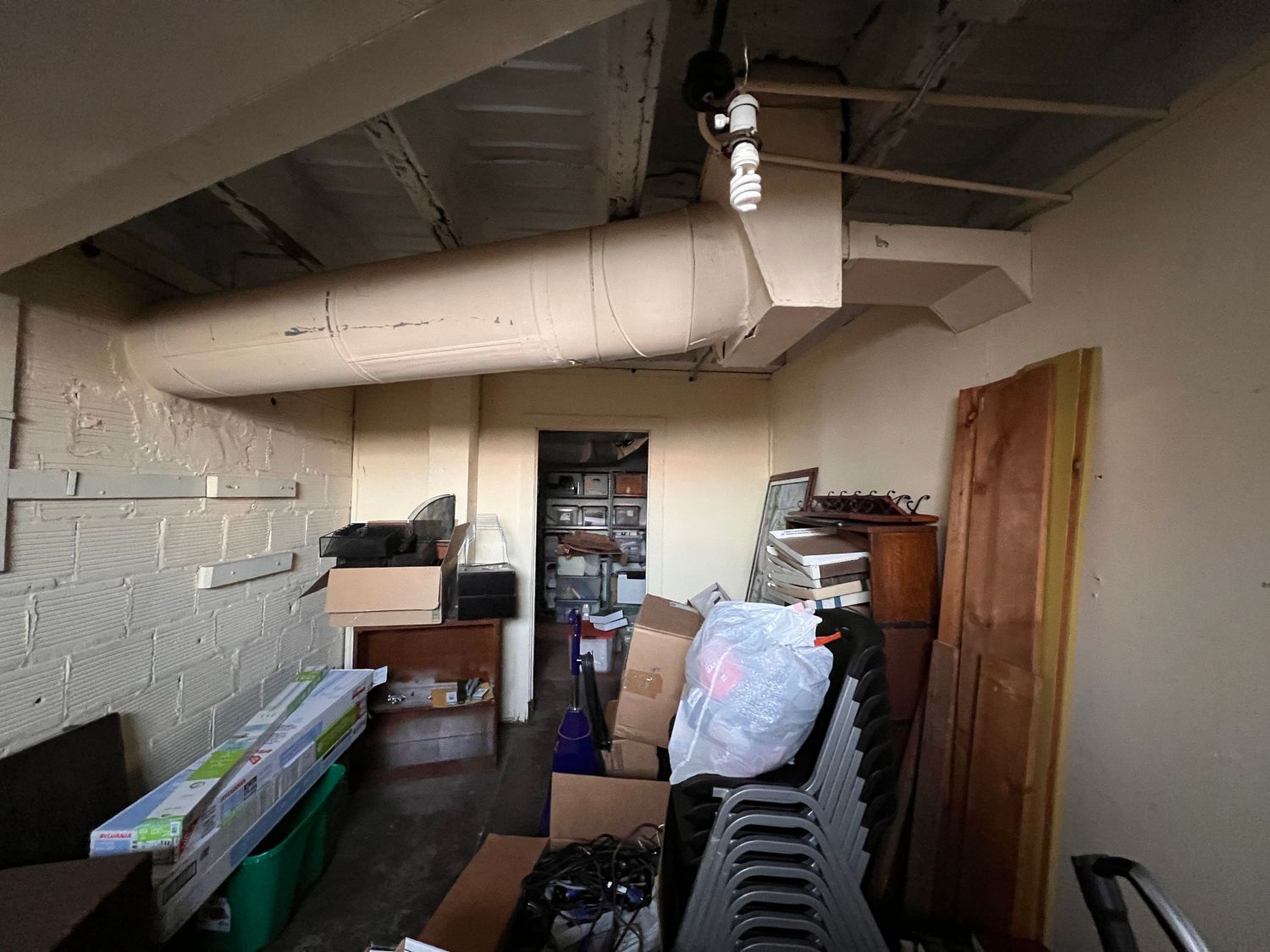 Unfinished basement storage area with exposed concrete walls and various boxes.