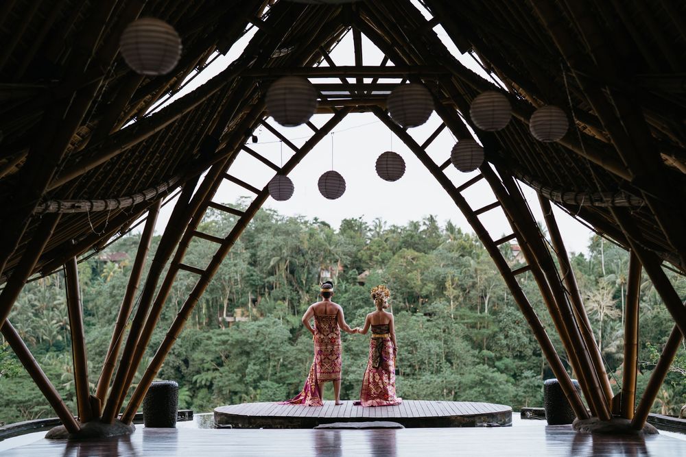 Wide view of a wooden pavilion structure in Bali with tropical forest surroundings.