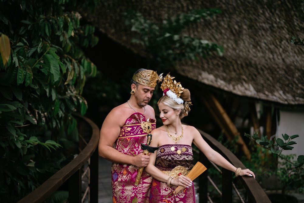 Traditional Balinese photoshoot with couple in red and gold ceremonial attire.