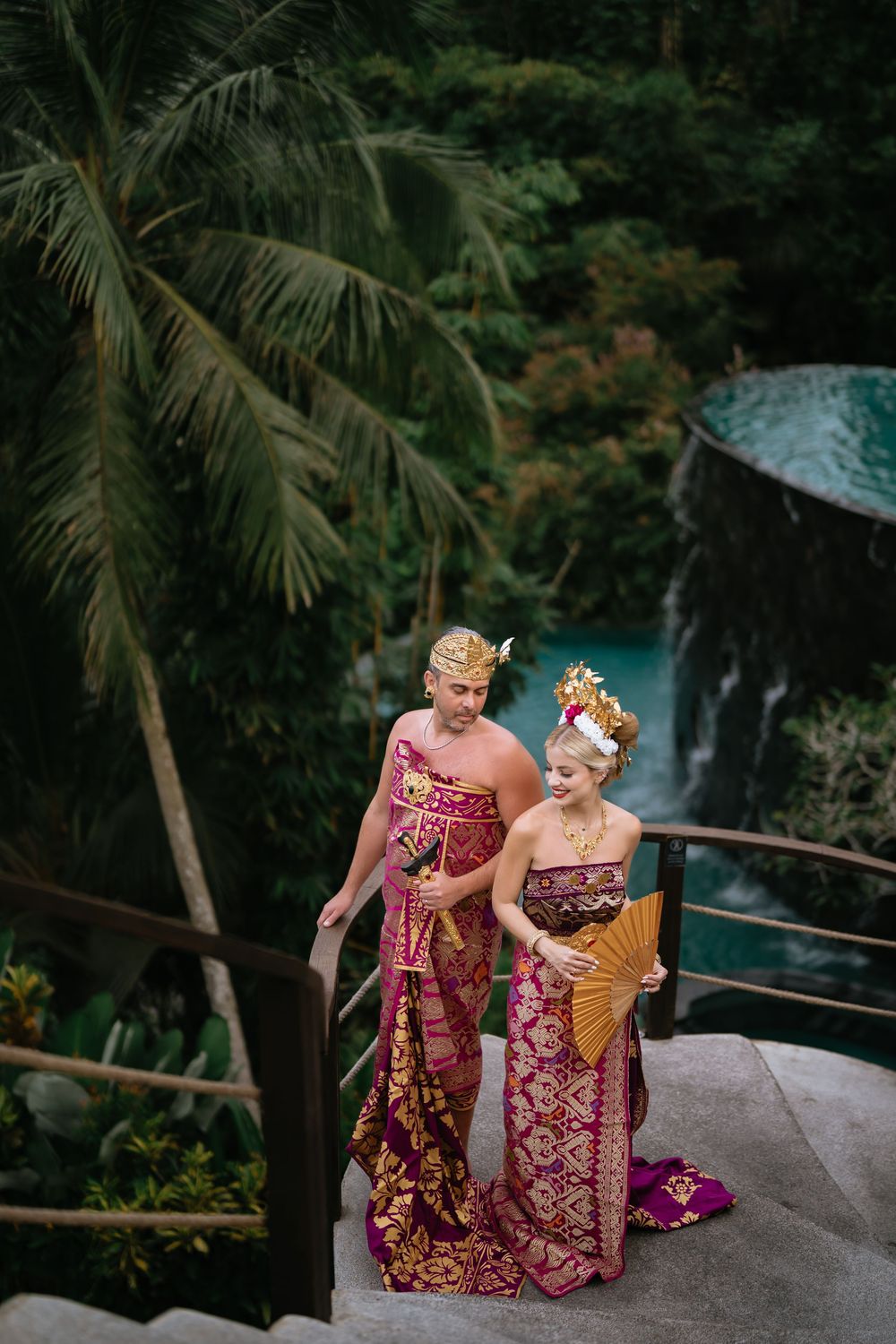 Romantic couple photo session in Balinese attire with tropical landscape backdrop.