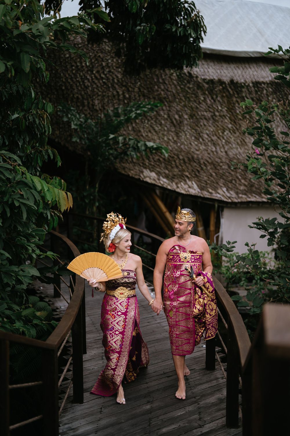 Traditional Balinese dance performance on a wooden walkway with traditional architecture in background.