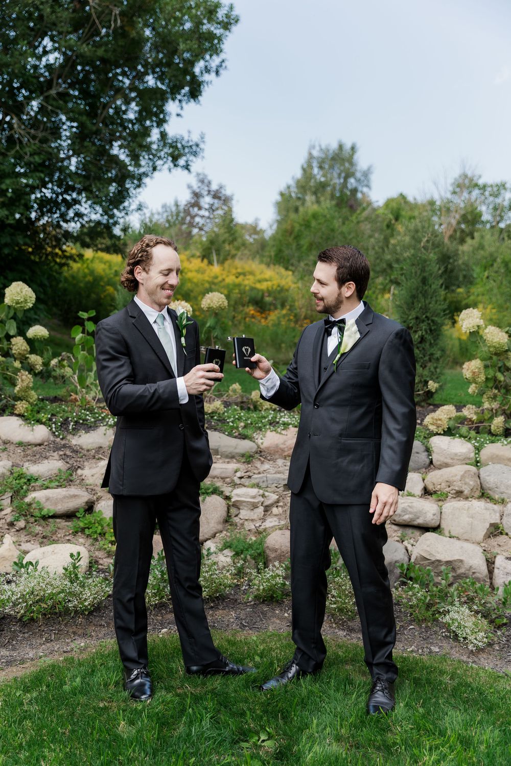 Groomsmen share drinks and laughter during outdoor wedding photoshoot at The Wren House in St. Jacobs, Ontario.