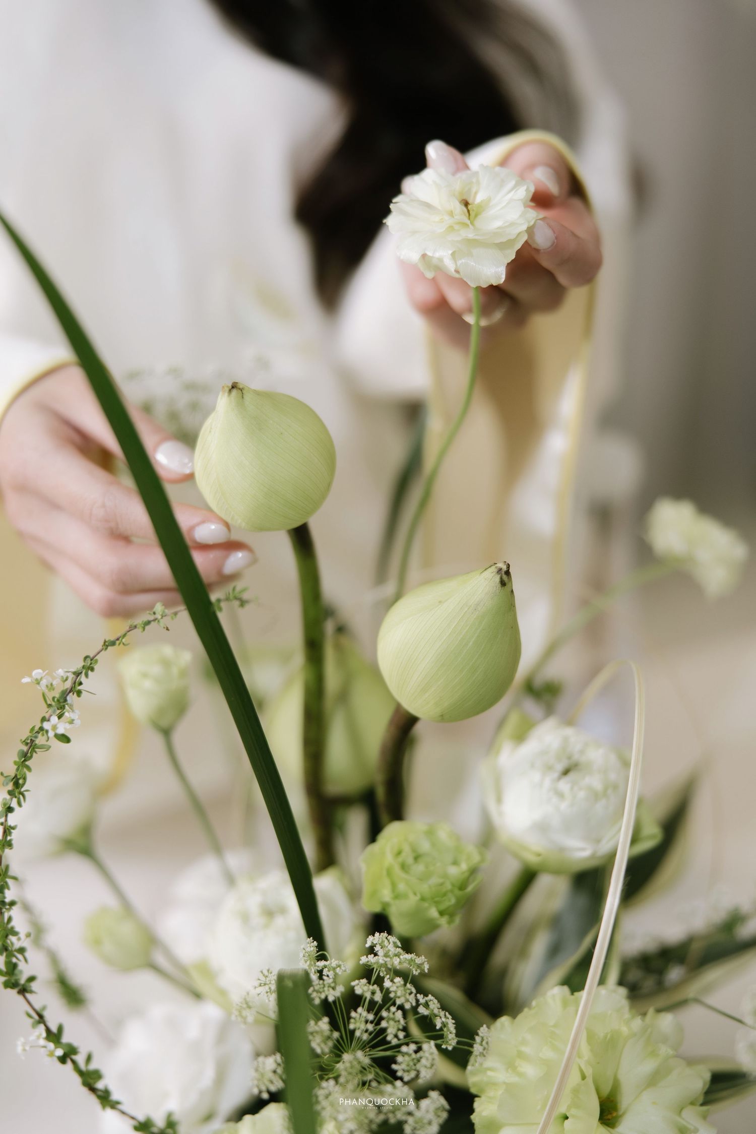 Close-up of elegant white and green floral wedding arrangement with lotus buds and delicate blooms.