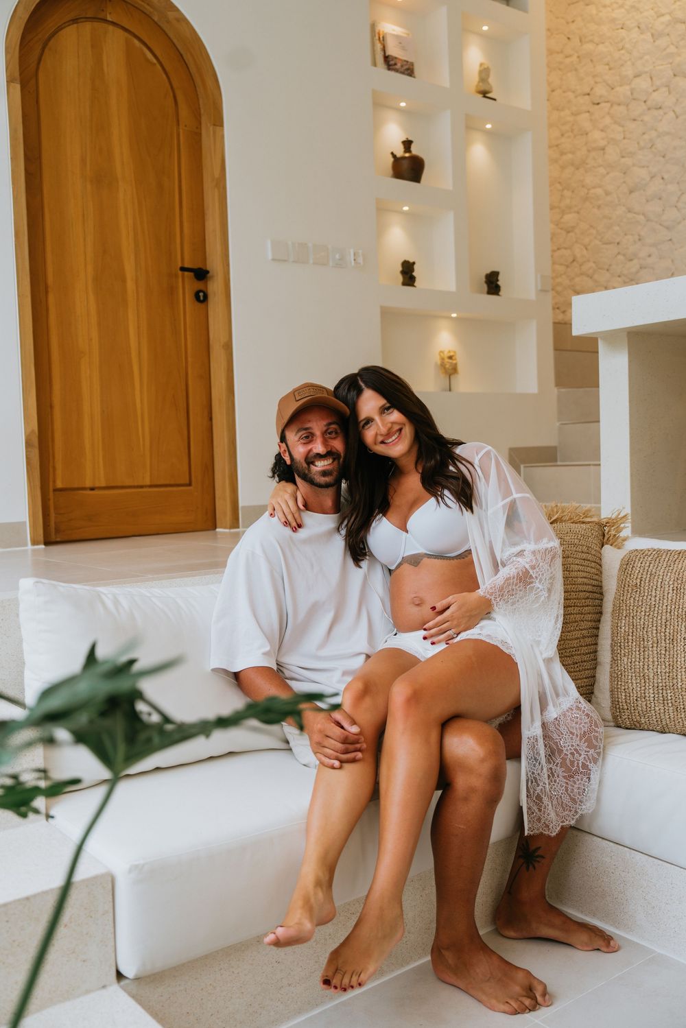 Couple sharing playful moments on white built-in seating with arched doorways.