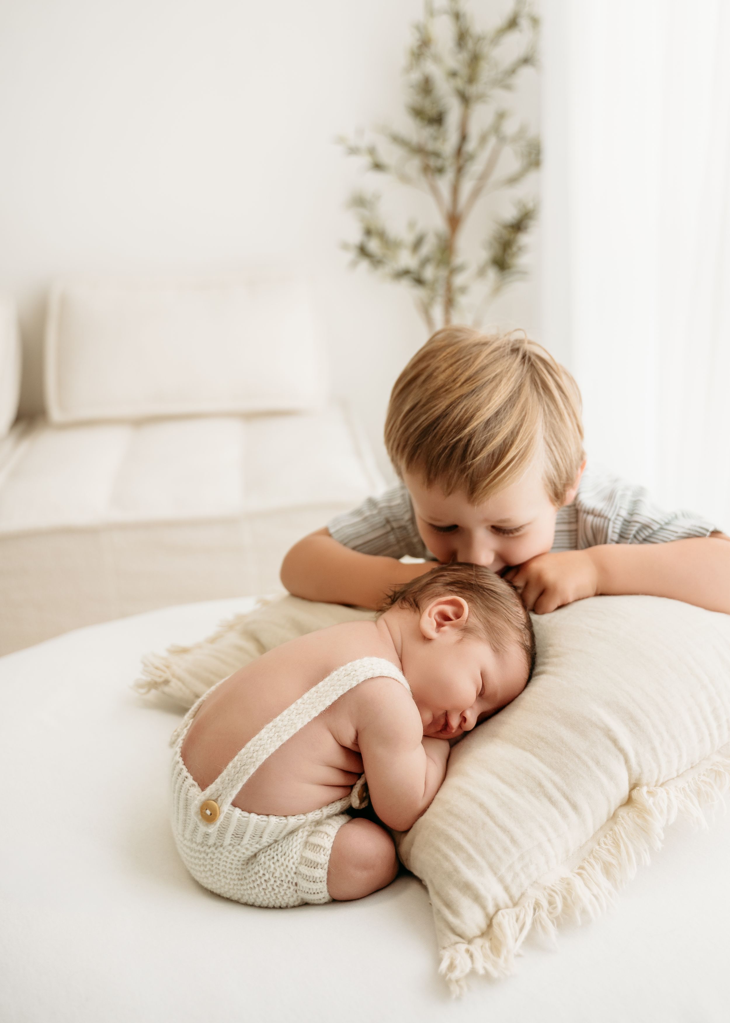 Peaceful newborn photography composition showing soft white bedding and delicate cream-colored textiles.