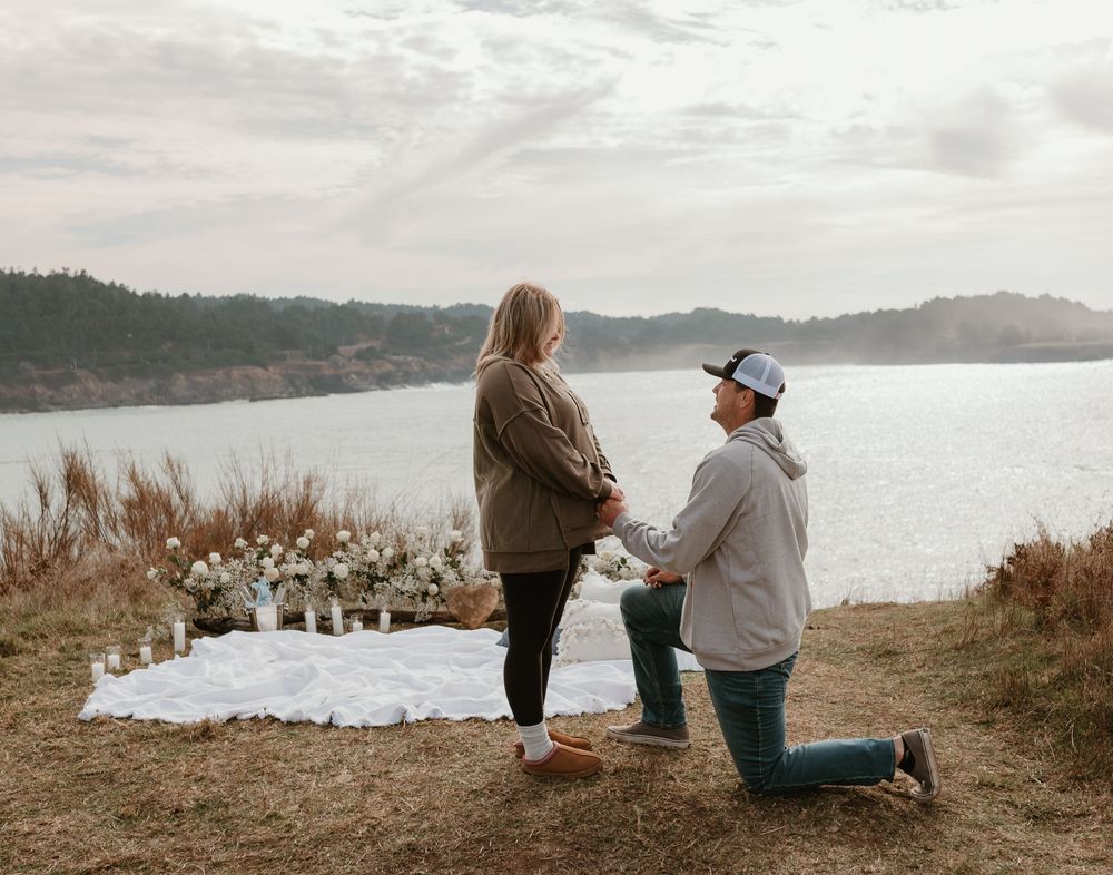 Two people share a special moment on a cliff with dried pampas grass and ocean views.