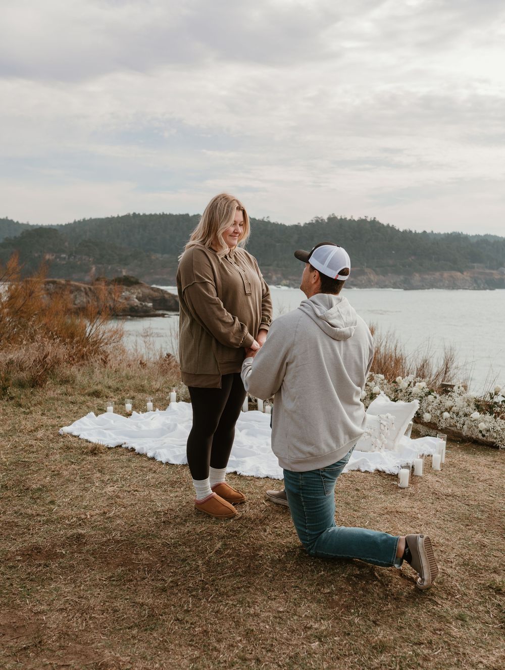 A couple shares a romantic moment on a cliff overlooking a scenic lake view.