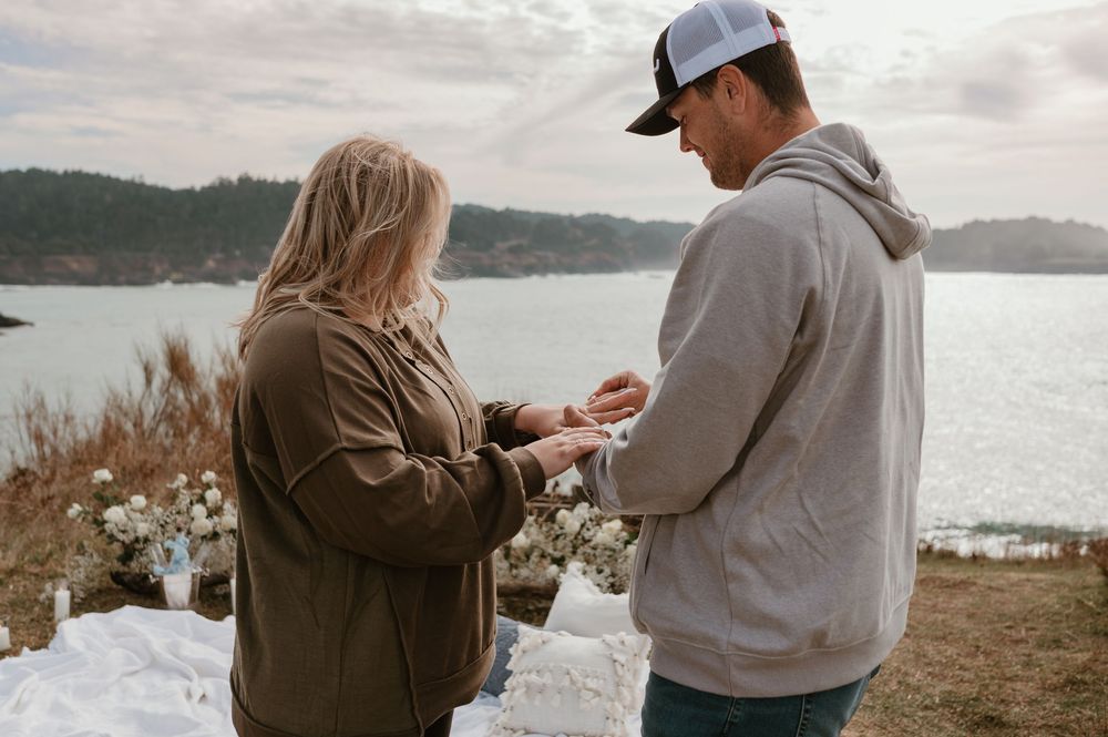 A romantic moment shared between two people on a cliff overlooking a lake.