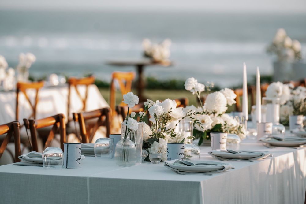 White and blush floral centerpiece arrangements with taper candles decorate elegant wedding reception tables.