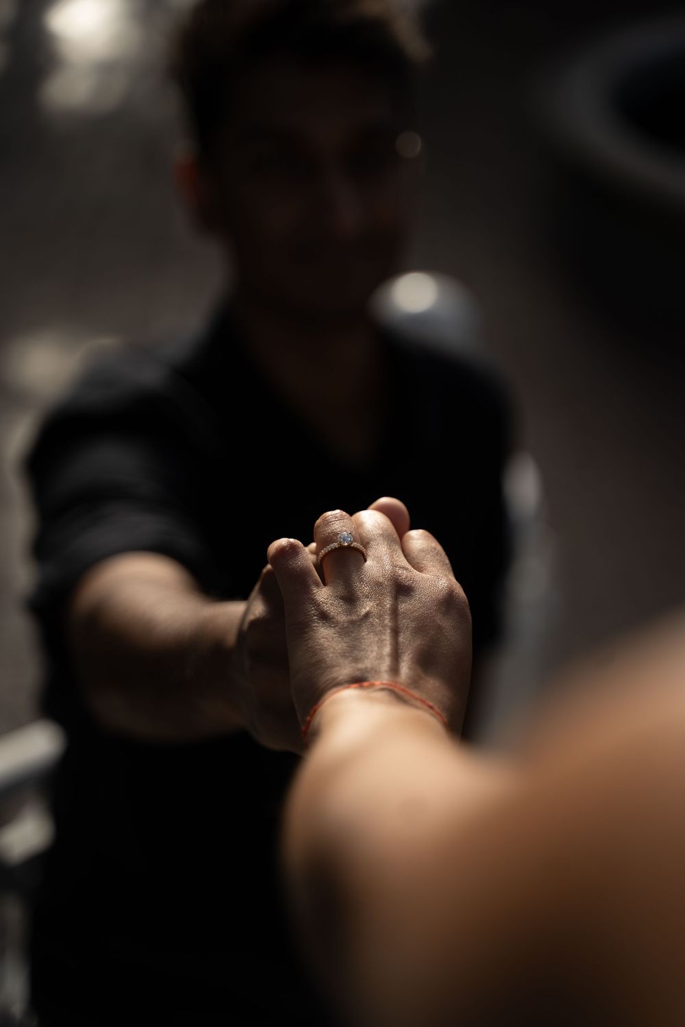 Two people clasping hands in a dark gym setting, man in black shirt reaching forward in a supportive gesture.