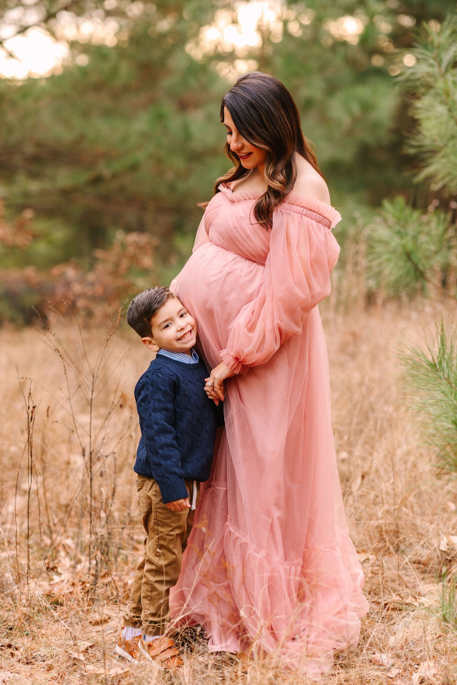 A touching moment in nature as a figure in a flowing pink dress interacts with a child in a navy shirt.