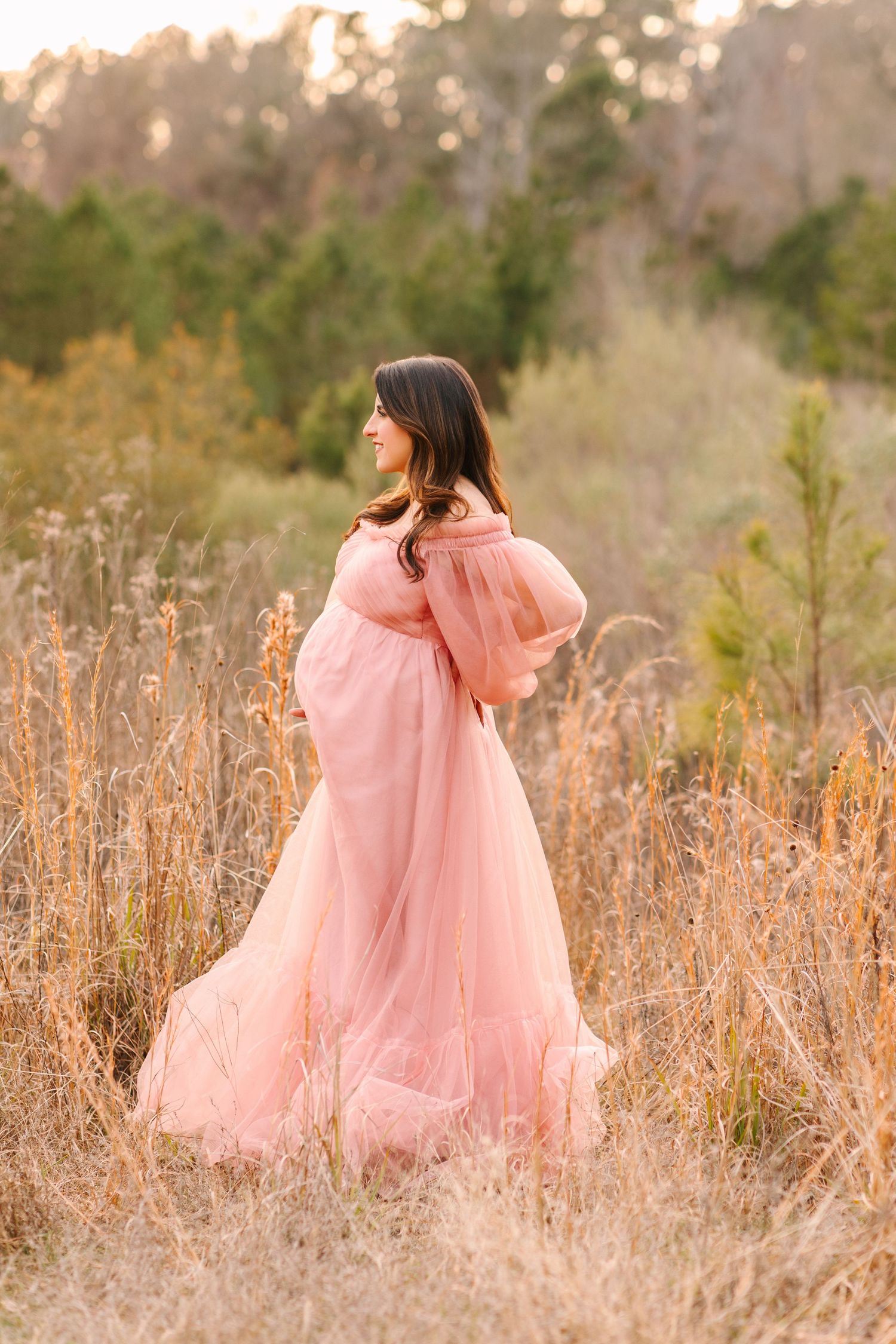 A girl in a flowing pink dress twirls through a golden autumn field at sunset.