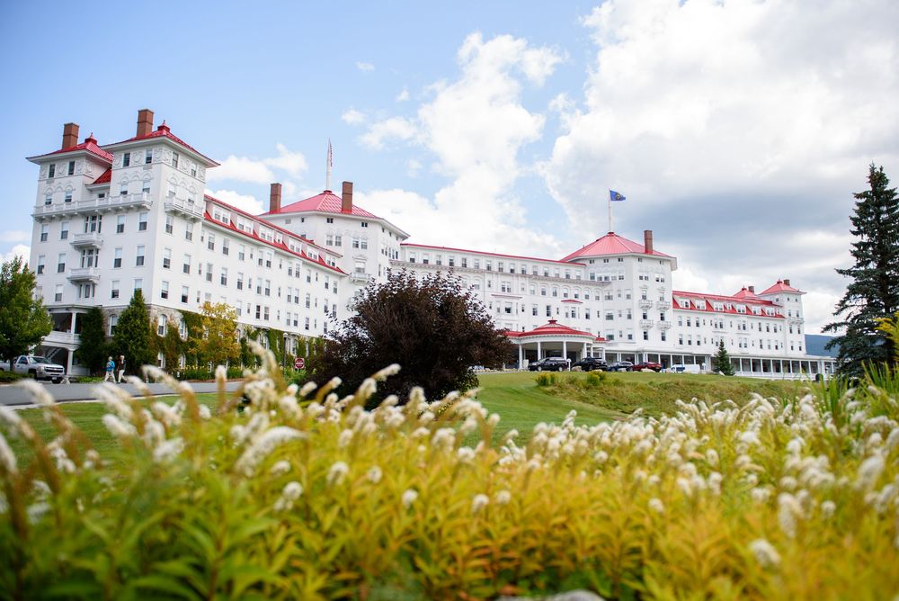 Historic Mount Washington Hotel with its grand white facade and red roof against a cloudy sky.