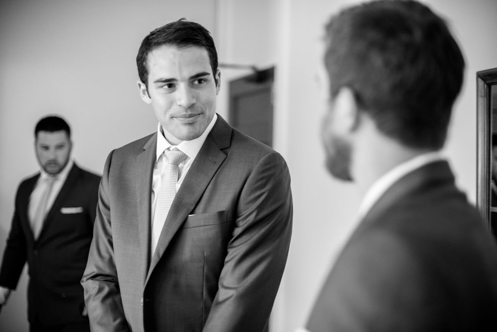 Black and white candid photos of groomsmen getting ready in formal attire.