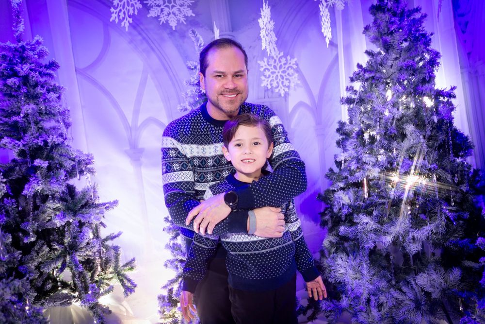 A winter wonderland photoshoot setup with purple lighting, Christmas trees, and snowflake decorations in a studio setting.