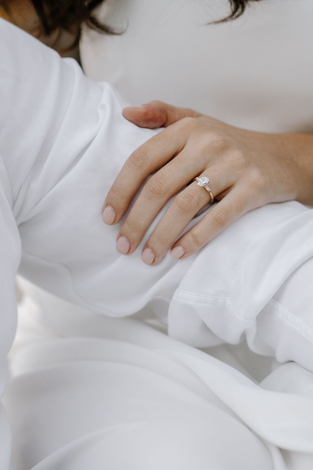 Close-up of an engagement ring on a white fabric with soft natural lighting.