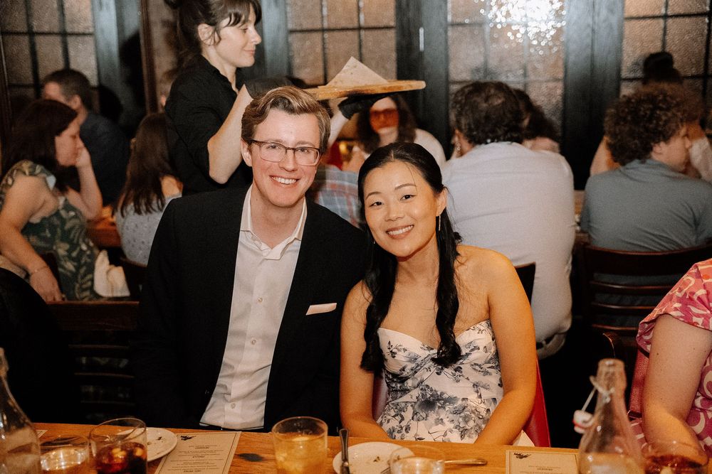 Wedding reception guests enjoying a lively celebration at tables in a dimly lit venue with festive atmosphere.