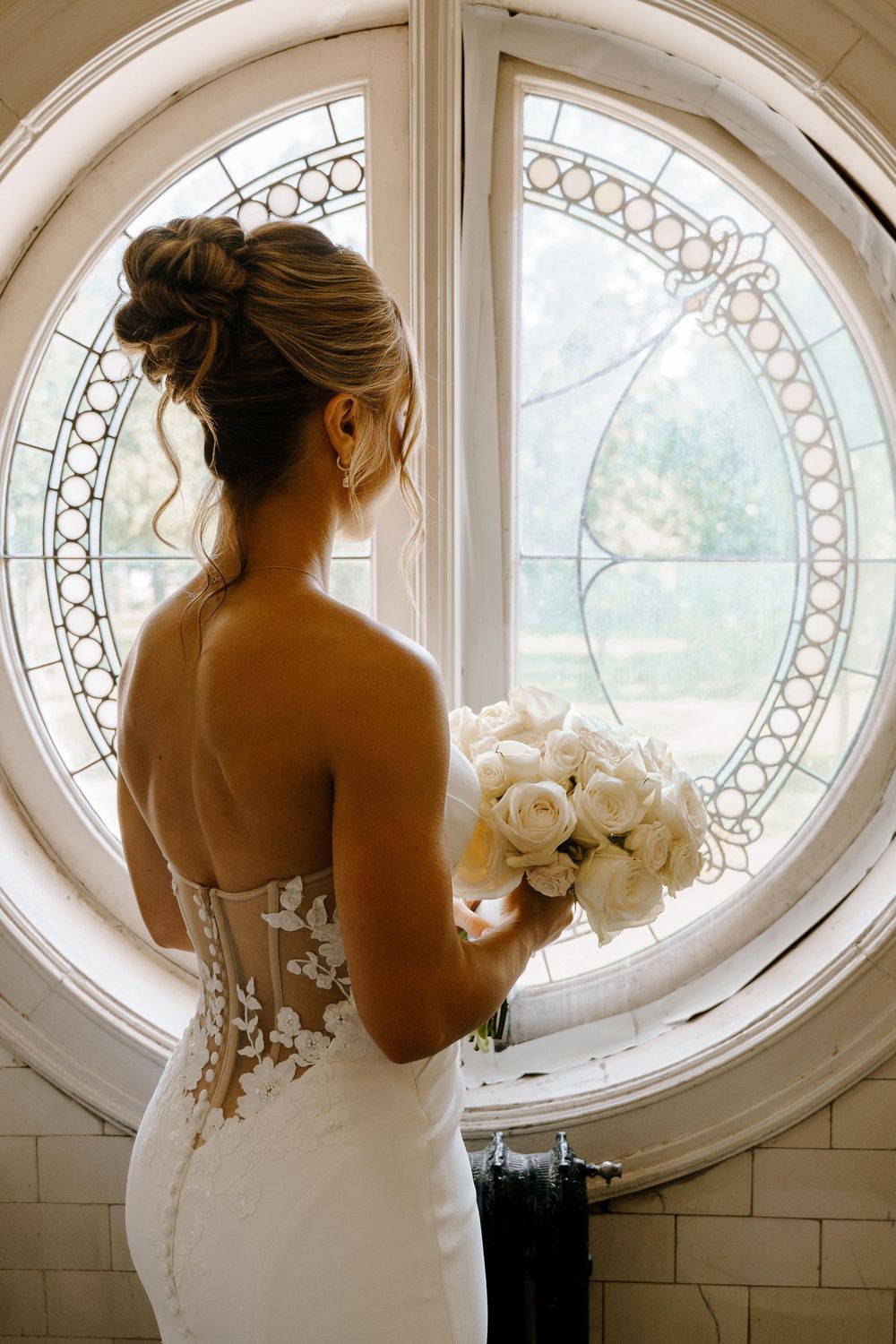 Three artistic sepia-toned photos of a bride in a white wedding dress standing by an elegant oval window with ornate details.