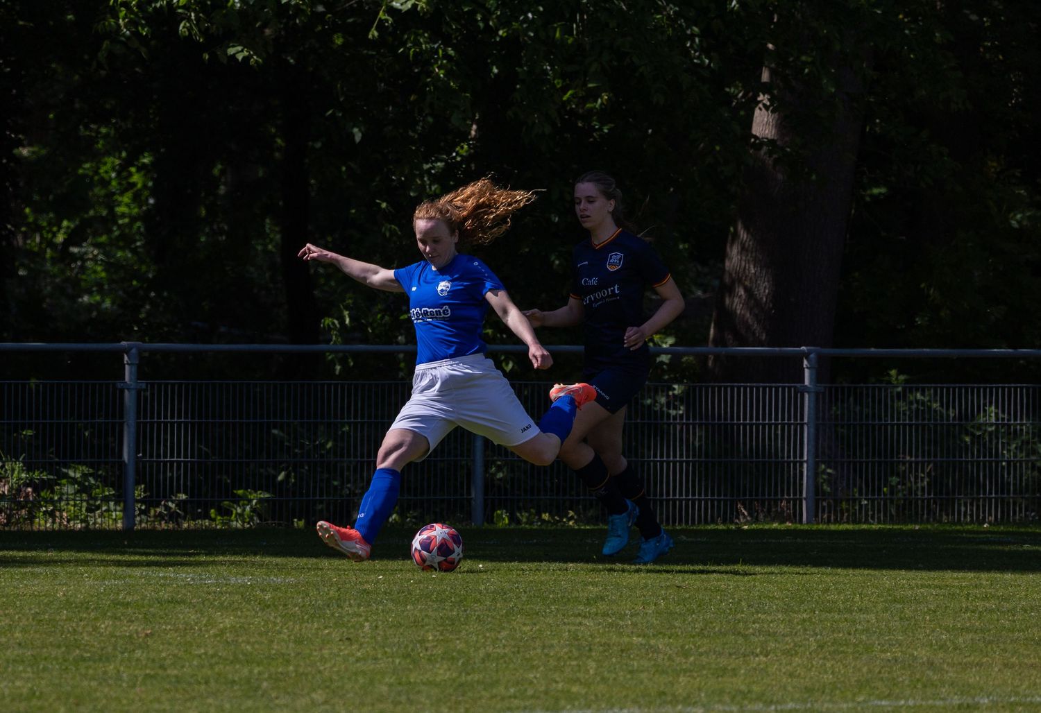Soccer player in blue uniform slides to block a shot during an intense match on a grass field.