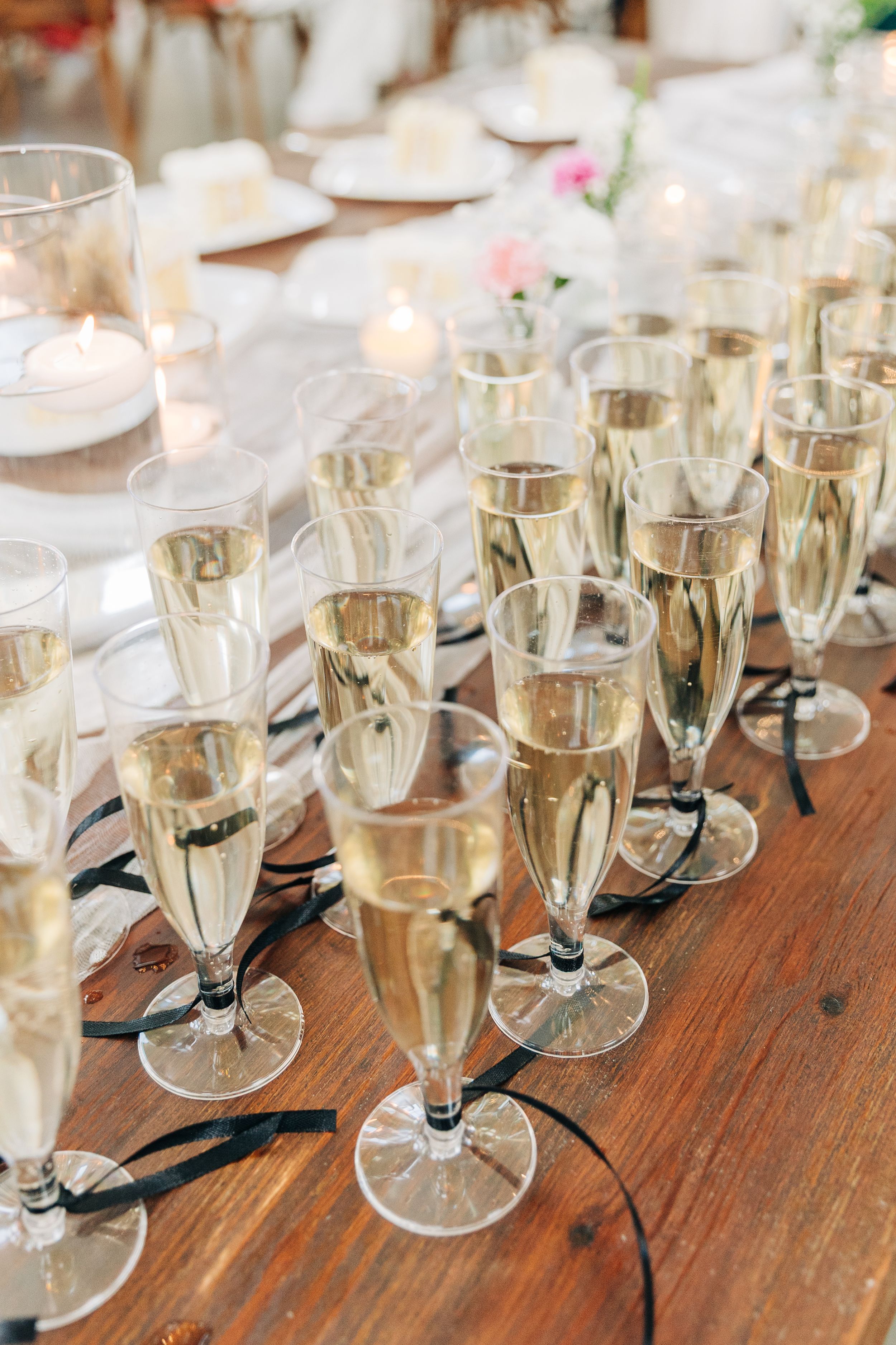 Multiple champagne flutes filled with bubbly wine rest on a rustic wooden table at wedding at Barn South