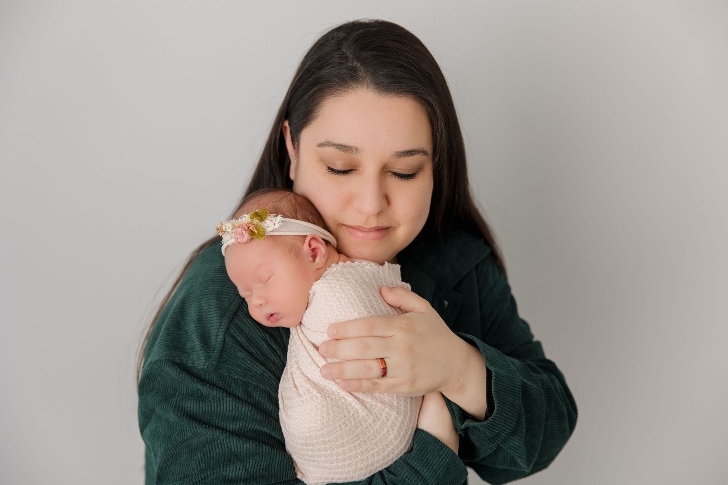 Close up of parent cradling and lovingly embracing newborn baby wrapped in light colored blanket.