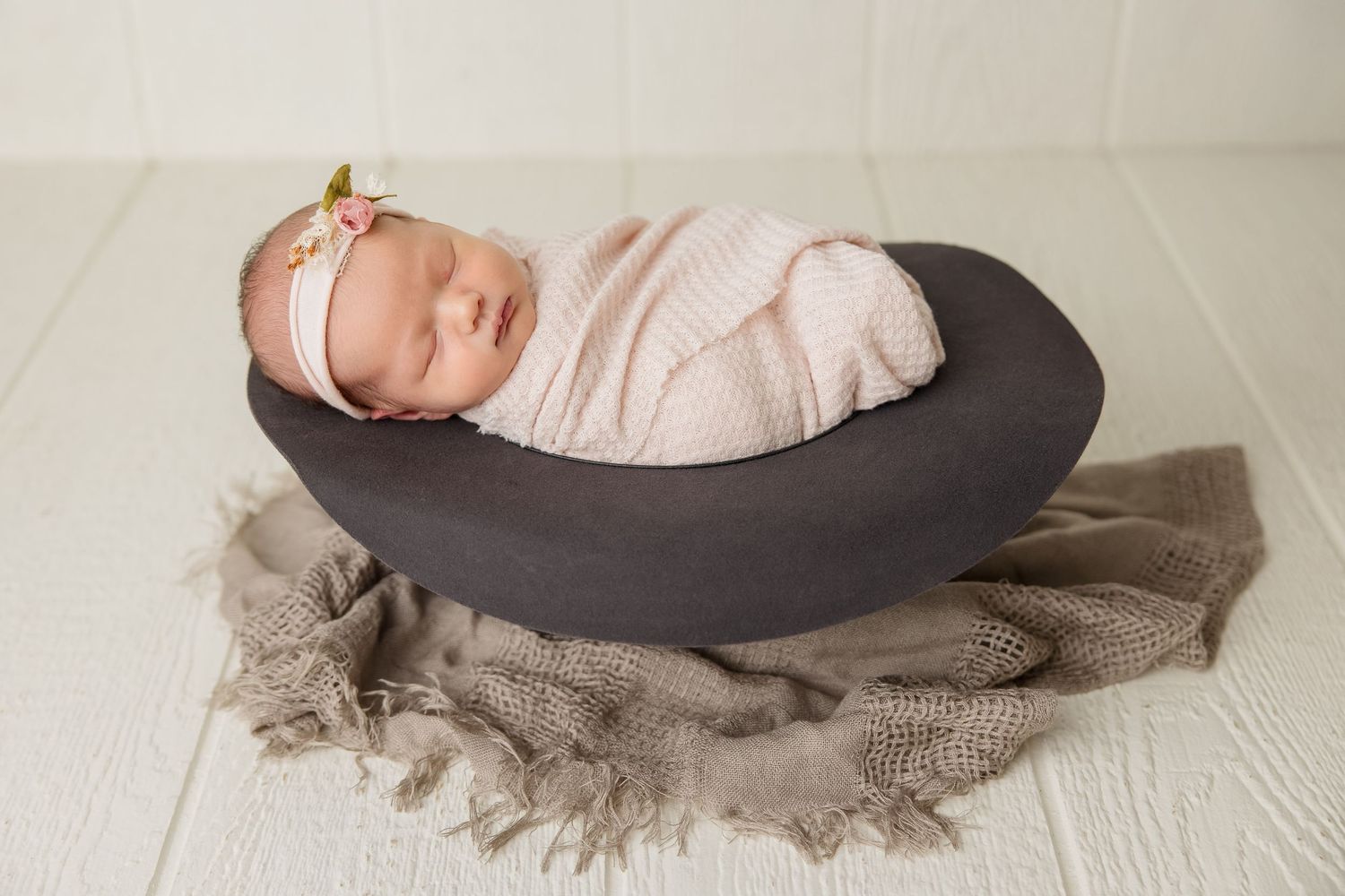 Artistic newborn photography with baby resting on curved posing pillow in soft lighting.