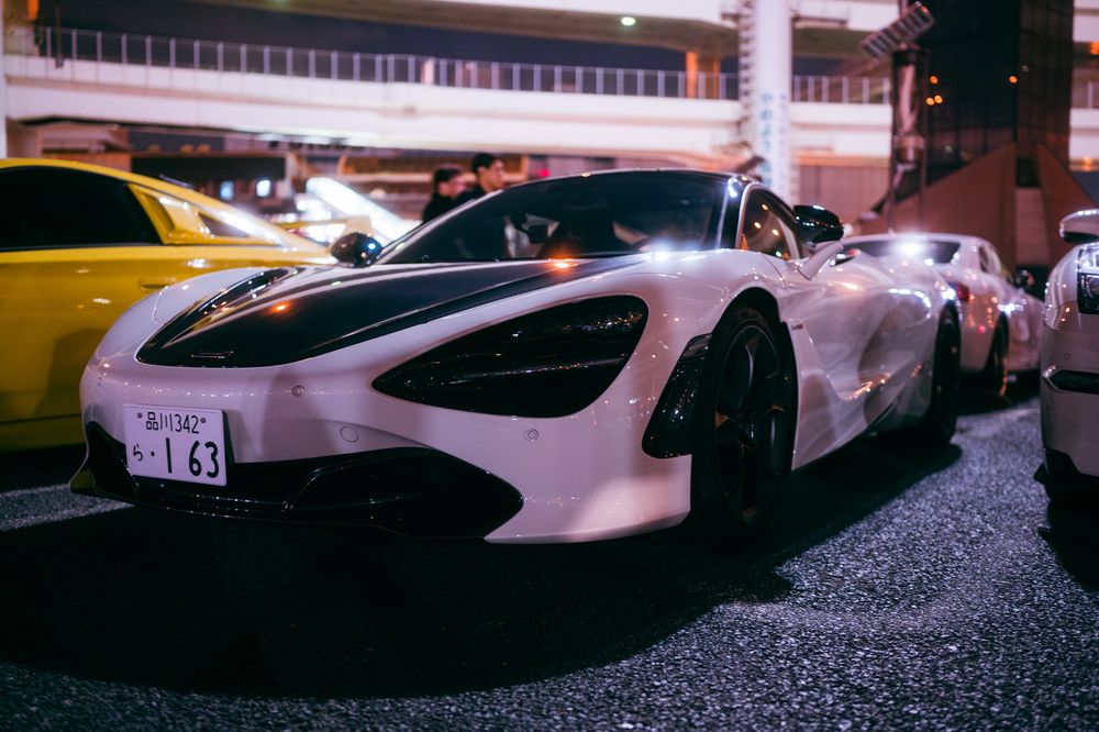 Pure white racing McLaren P1 GTR supercar parked in a covered area with other luxury sports cars beside it.