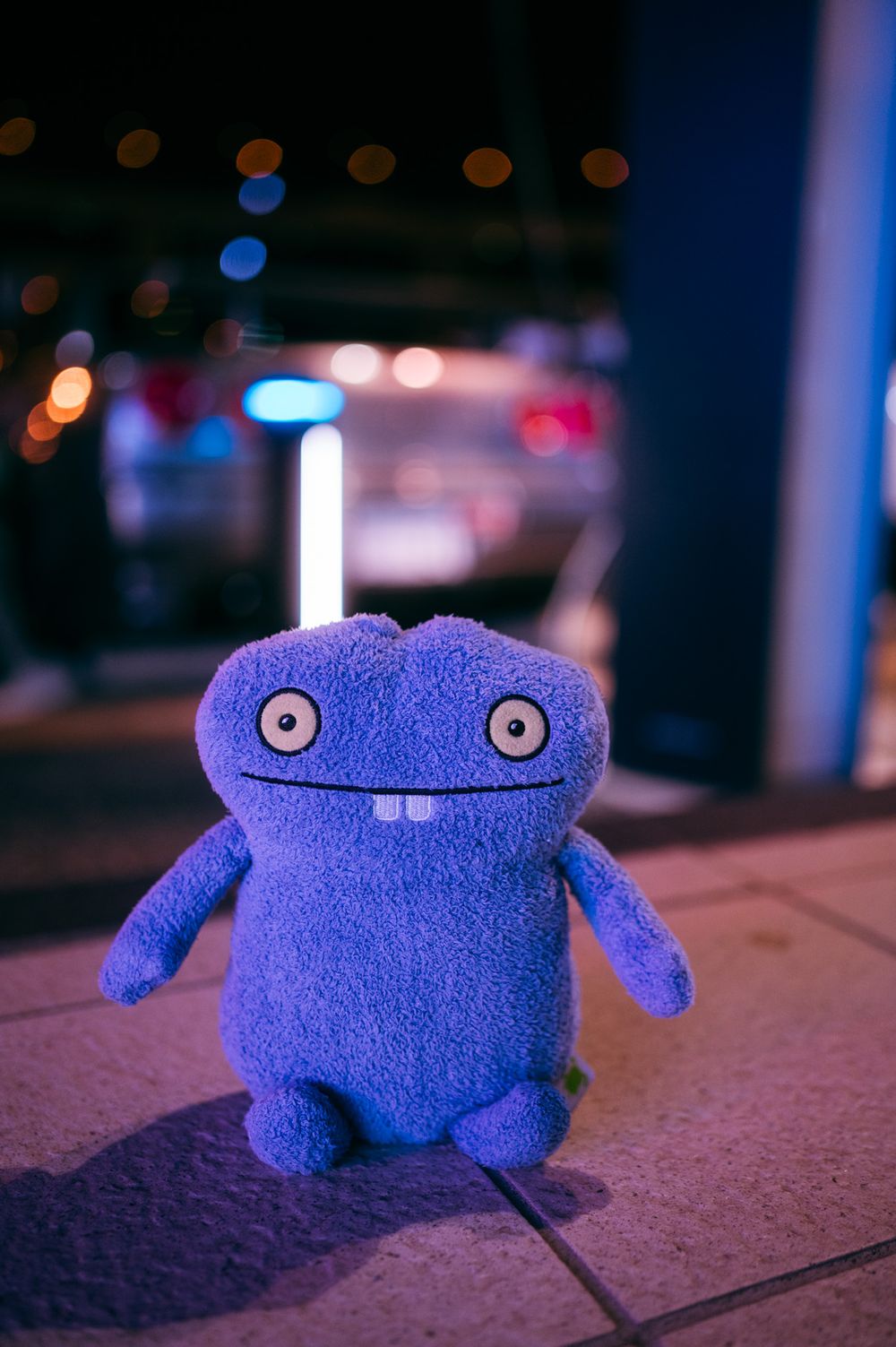 A series of shots showing a cute blue plush toy monster sitting in different poses under moody nighttime lighting.