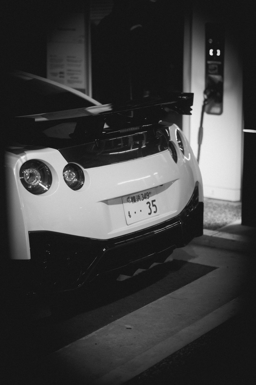 Black and white shots of a sports car's rear end showing sleek bodywork and taillights.