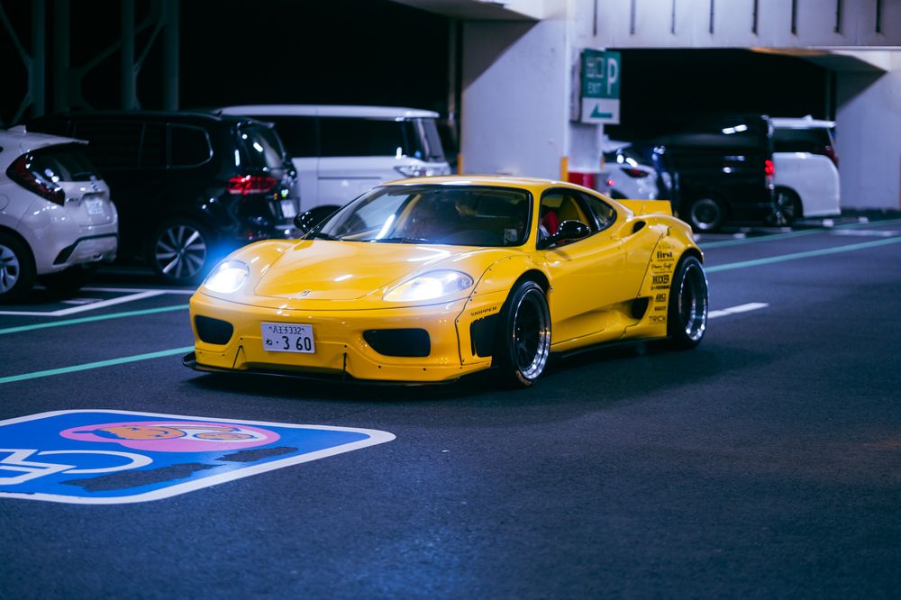 Yellow sports car parked on a dark street next to other parked vehicles at night.