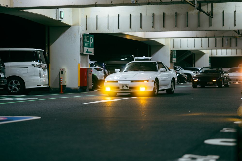 A dark underground parking garage with cars and yellow lights creating an atmospheric scene.