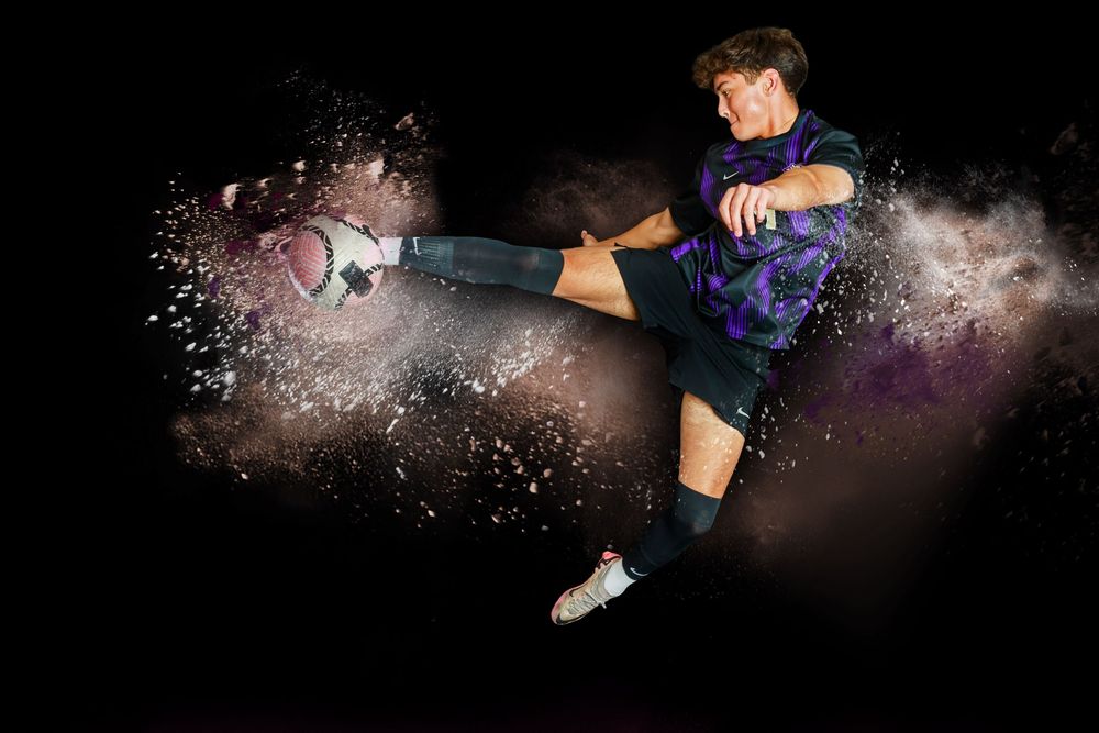 Artistic dance sequence showing figure leaping through colorful powder explosions against black background.