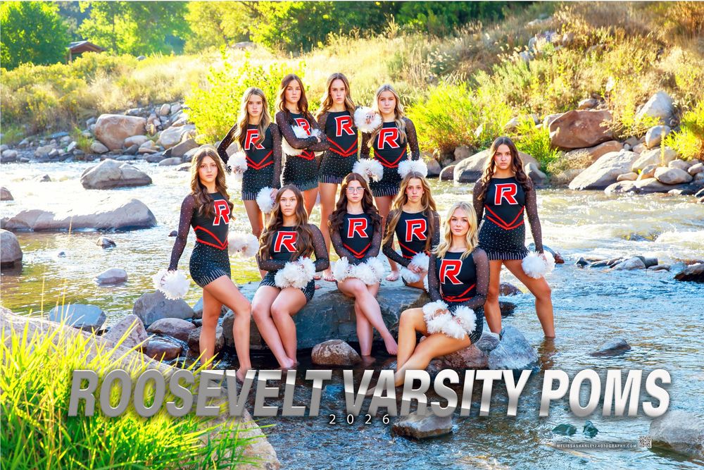 Cheerleaders in red and black uniforms pose together on rocks near a river during an outdoor photo session.
