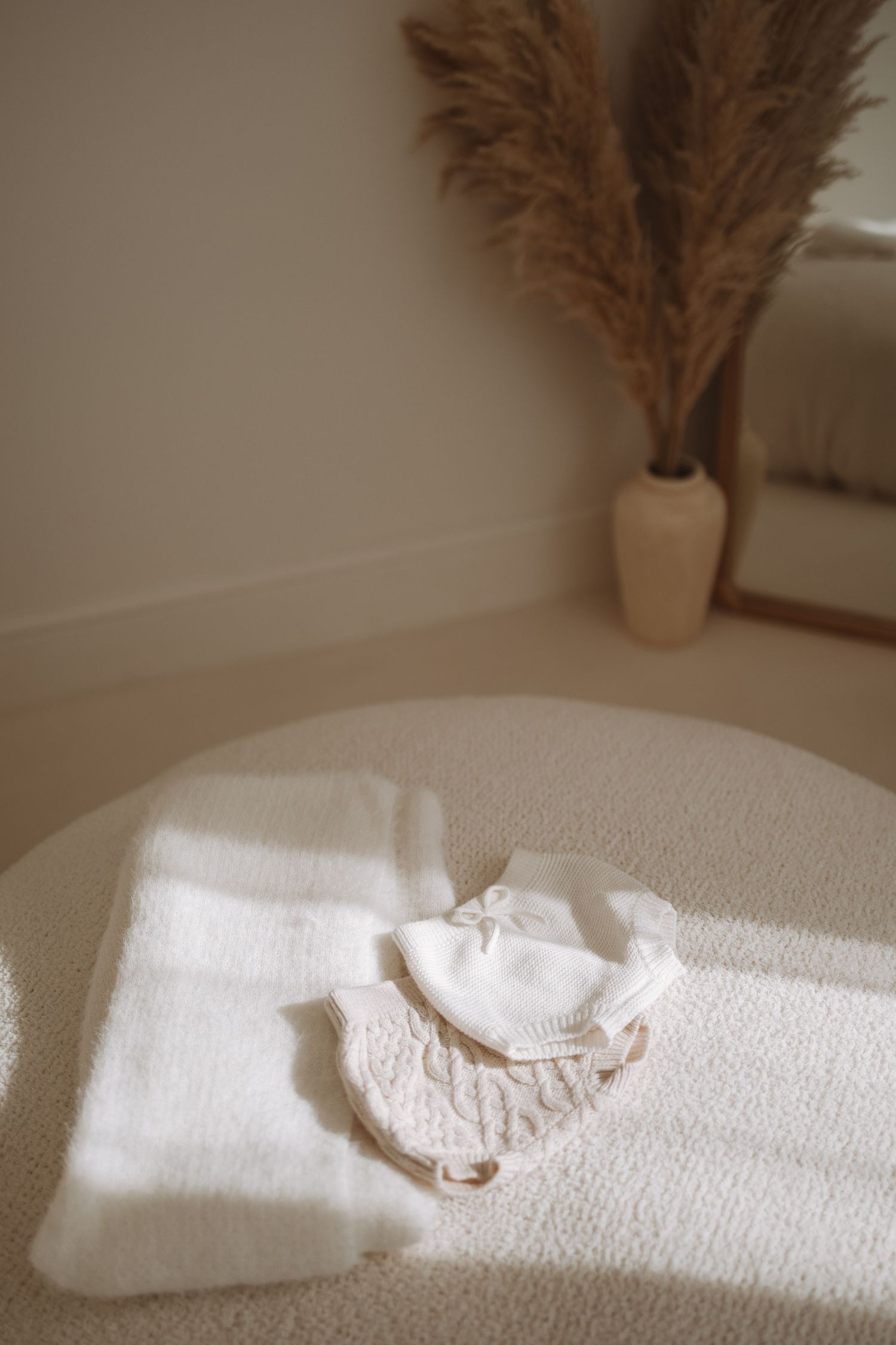 Sequence of minimalist photos showing sunlight casting shadows across white bedding with a dried pampas grass decoration.