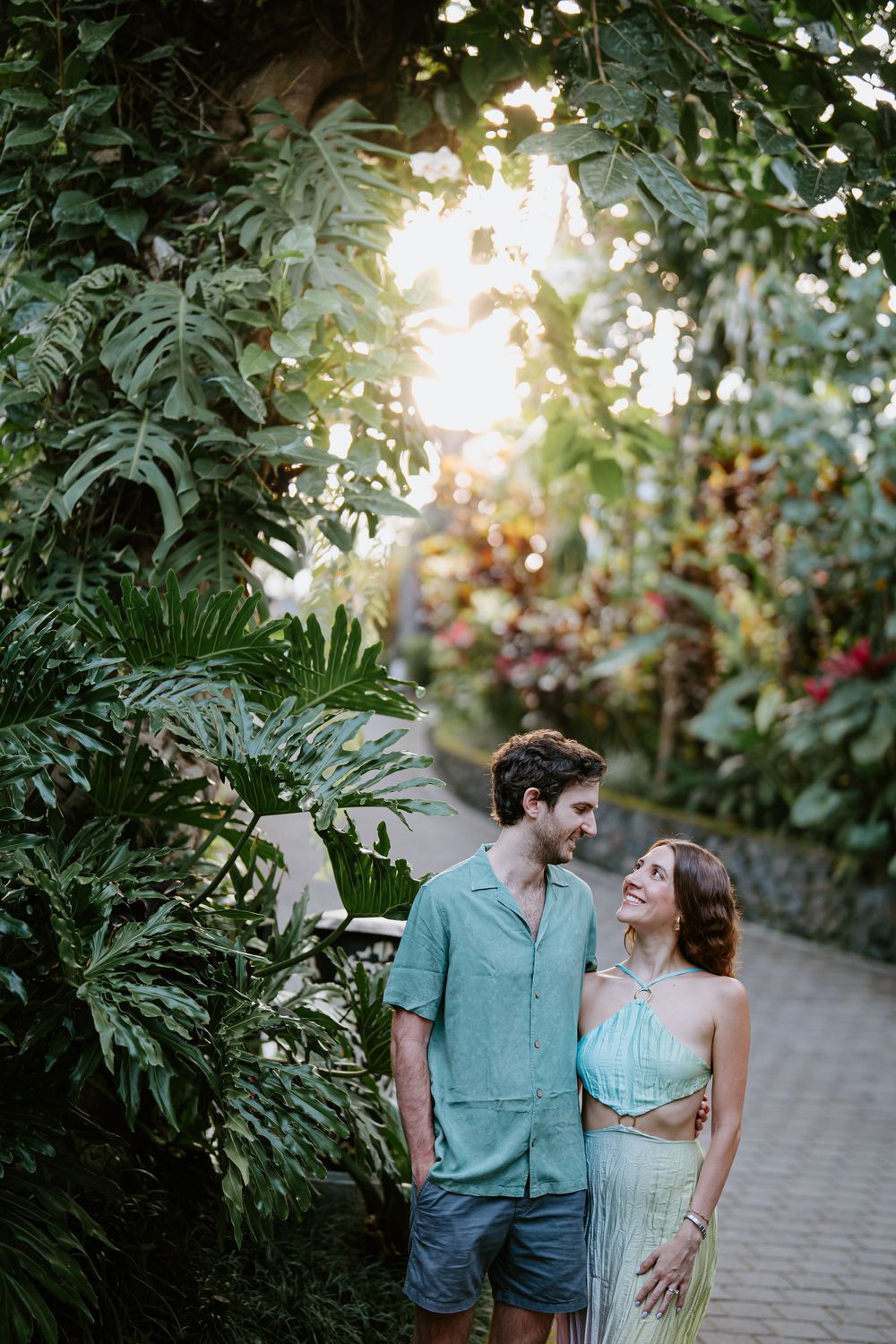 Romantic garden path photoshoot with soft evening light filtering through tropical foliage.