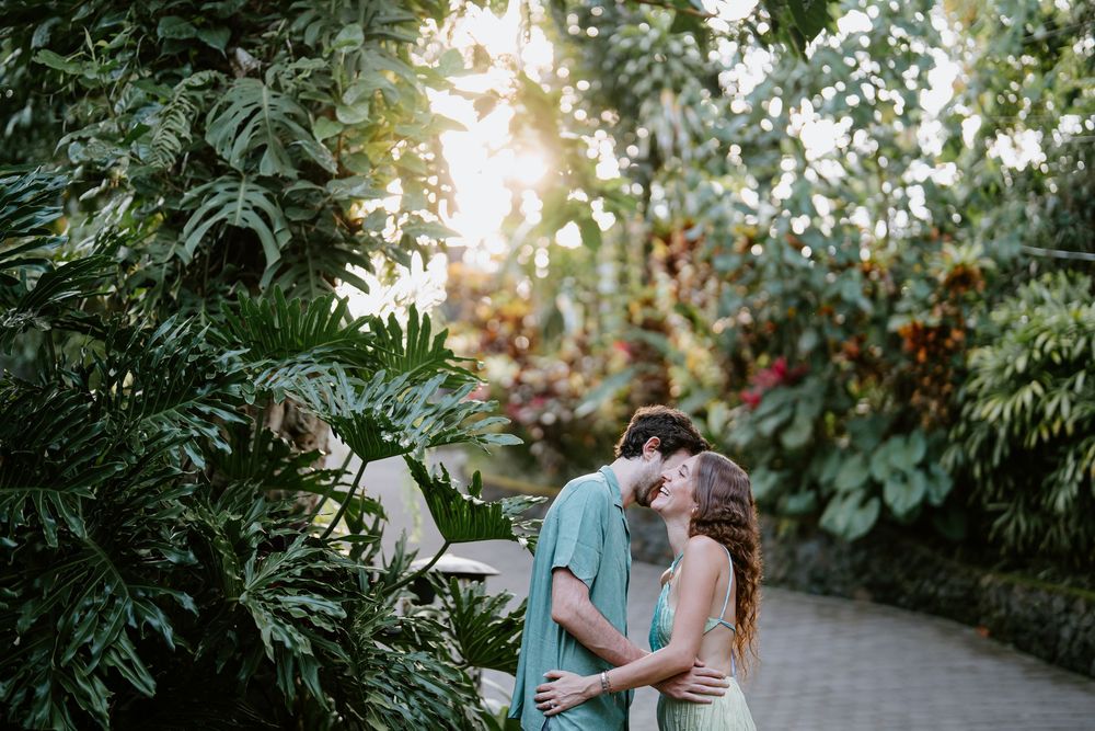 Couple shares tender moments along a garden walkway surrounded by lush greenery.