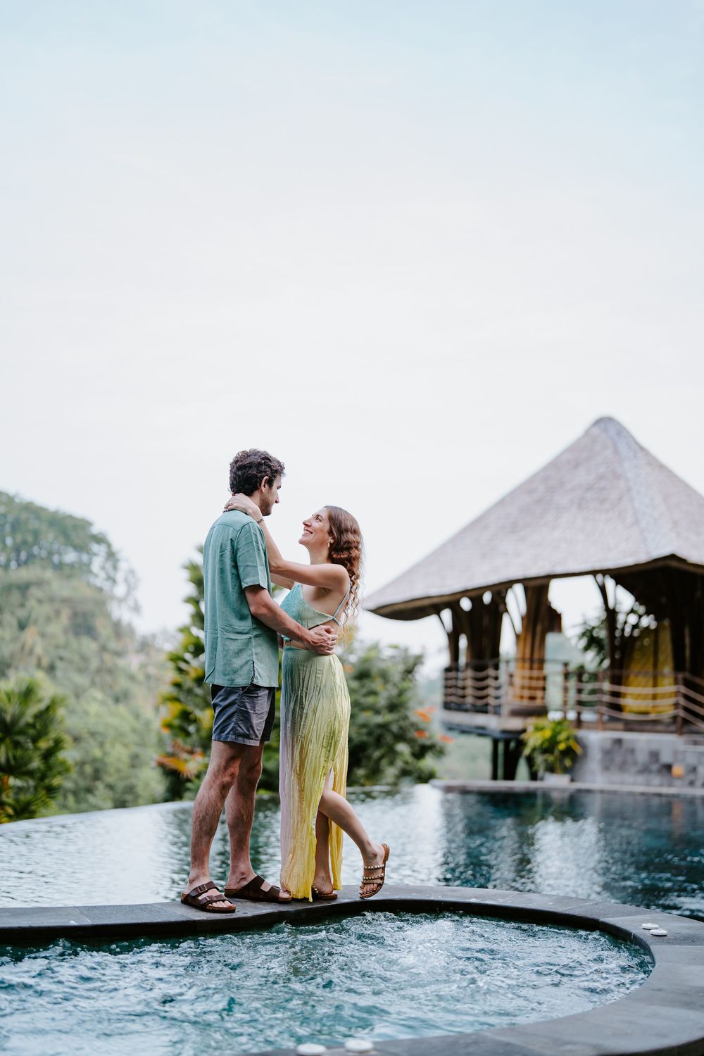 Romantic couple sitting at the edge of an infinity pool overlooking mountain views at a luxury resort.