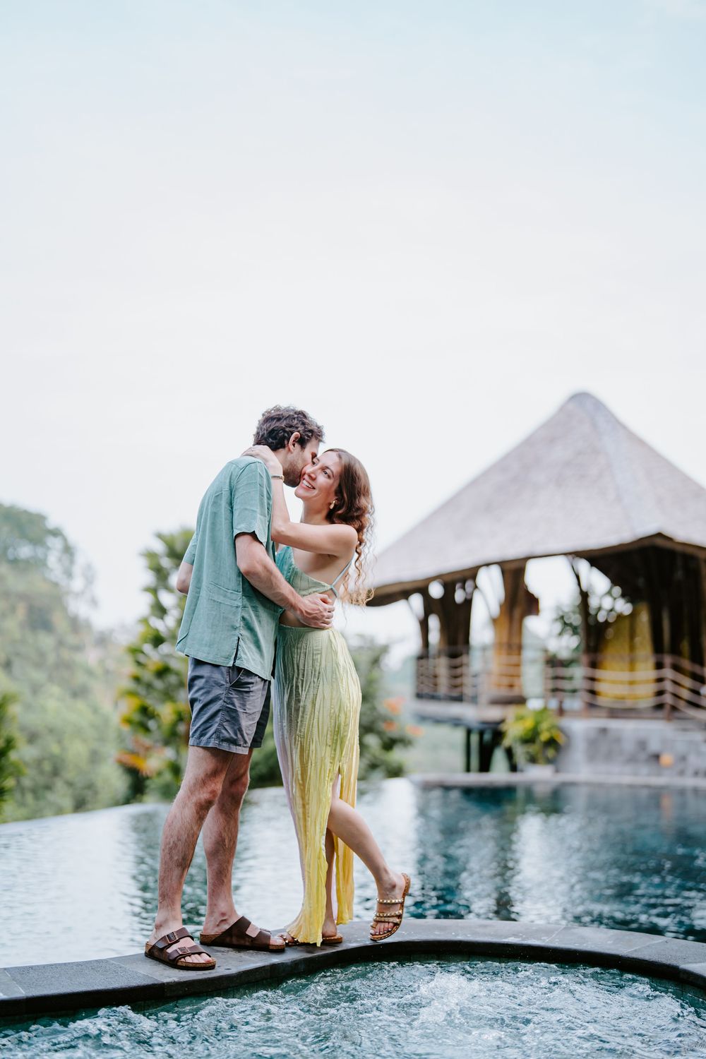 Romantic couple sharing intimate moments by a scenic infinity pool with mountain views.