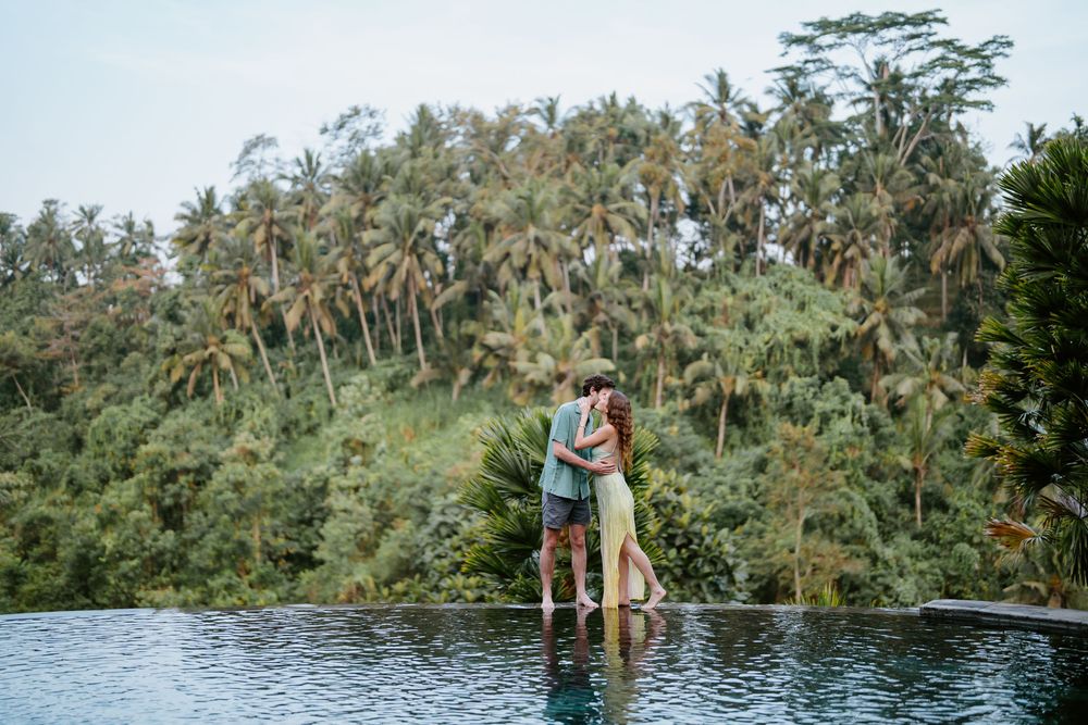 Panoramic view of infinity pool overlooking dense tropical palm forest landscape.