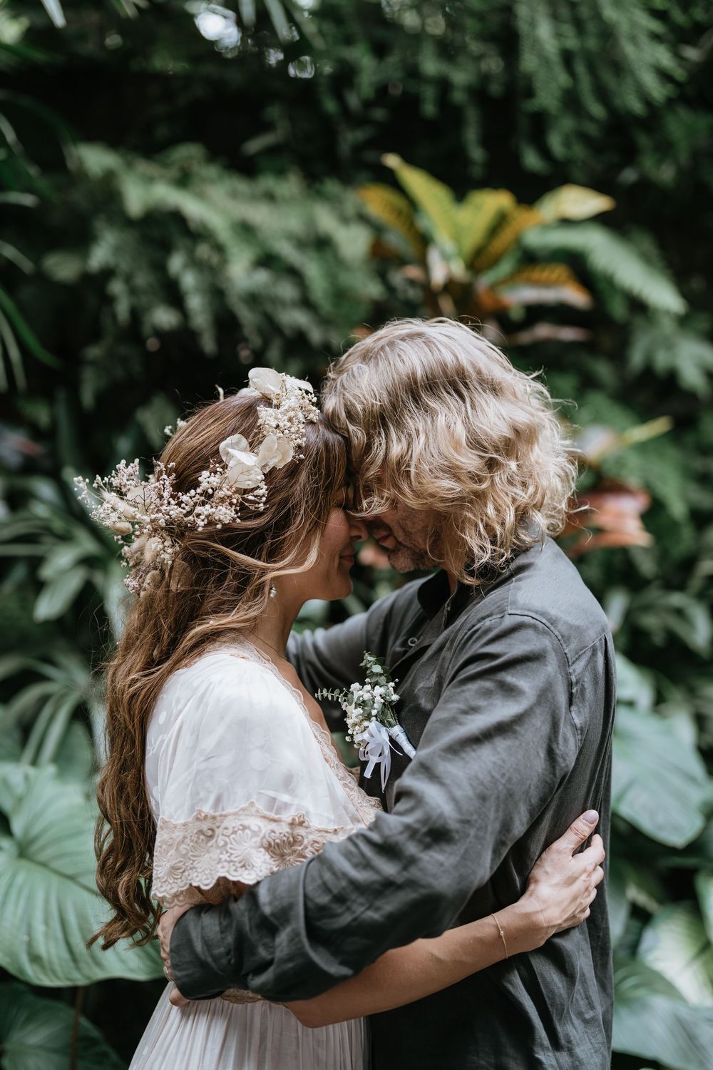 Couple embraces among tropical foliage during wedding photoshoot.