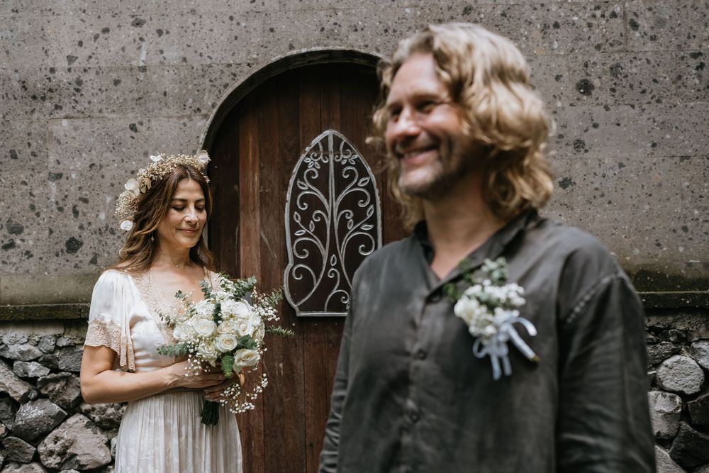 Couple poses against textured concrete wall during wedding portraits.