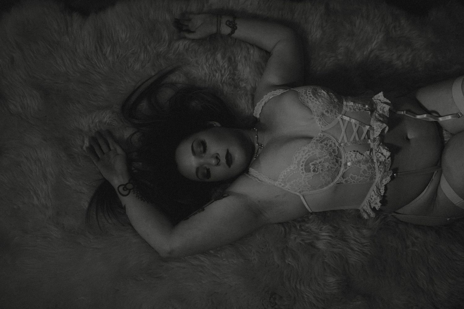 Artistic black and white portrait photograph with dramatic shadows and lighting against a dark background.
